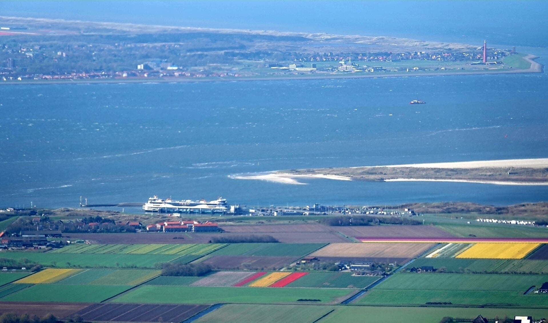 Het Marsdiep tussen Texel en Den Helder met de bollenvelden in de Prins Hendrikpolder op de voorgrond.