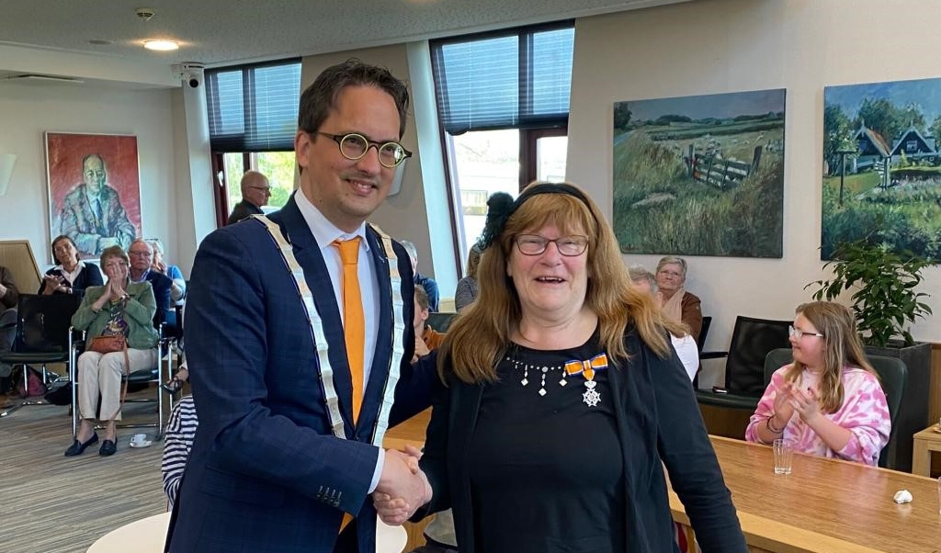 Mary Velkamp krijgt van burgemeester Uitdehaag felicitaties voor haar koninklijke onderscheiding. 