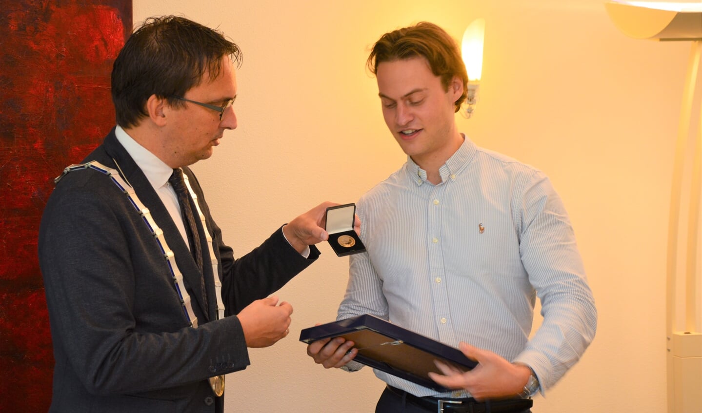 Redder Bram Daniëls ontvangt de bronzen medaille van de KMRD uit handen van burgemeester Uitdehaag. 