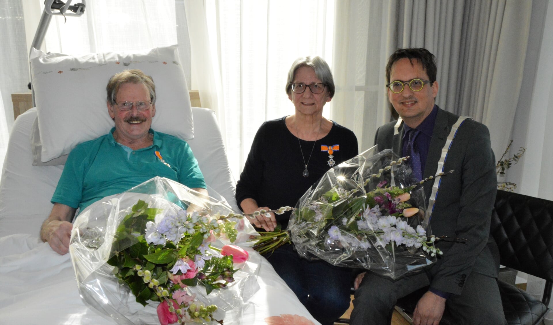 Harry en Geertje Schrama met hun Koninklijke Onderscheiding, zojuist opgespeld door burgemeester Michiel Uitdehaag. 