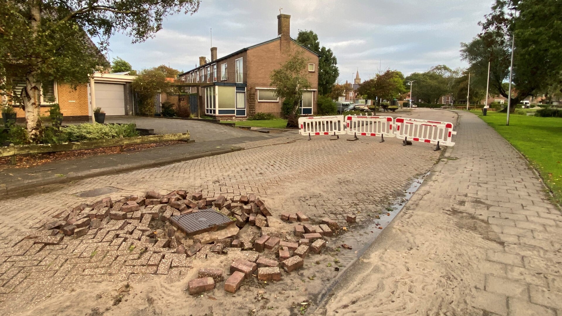 Het kapotte wegdek rond de rioolput.