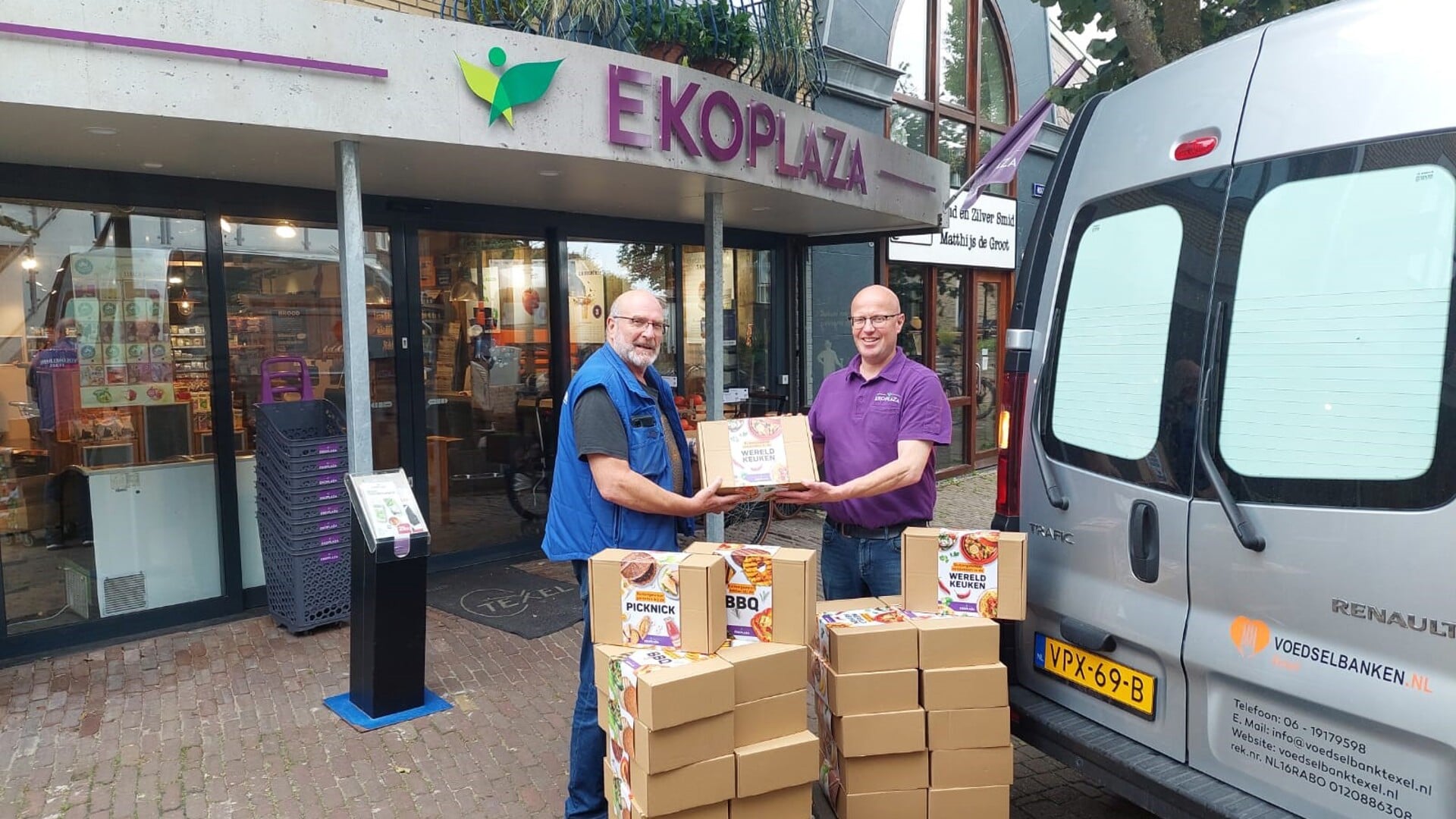 Dwight Penha neemt de boodschappenpakketten in ontvangst van Mattijs Dieks van Ekoplaza in Den Burg.
