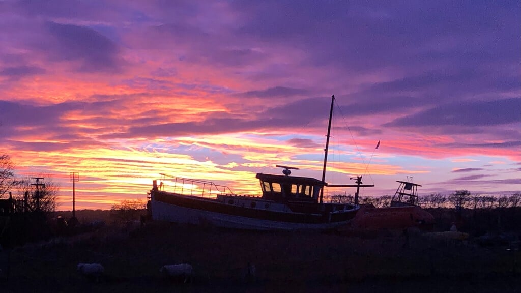 De boot bij Flora met de zonsondergang op de achtergrond.