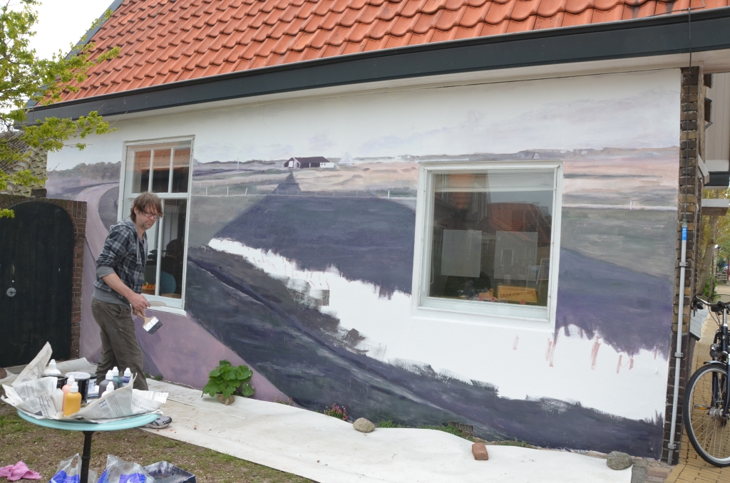 Adzer van der Molen schildert het omliggende landschap op de muur. 