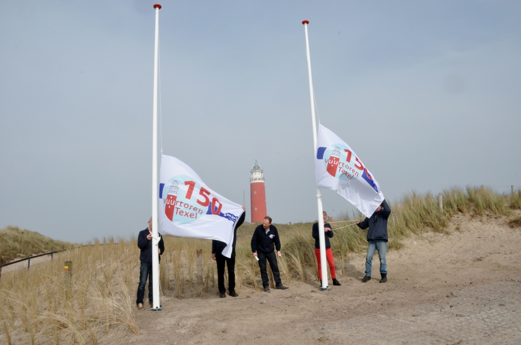 Medewerkers van Stichting Texels Museum hijsen de jubileumvlaggen bij de nieuwe entree. 