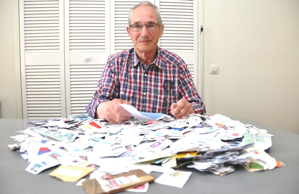 Joop Kramer met een verzameling postzegels op stukjes envelop voor het goede doel.
