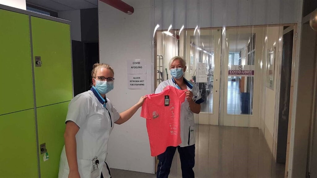 Mariska Koenders overhandigt een shirt van de Halve Marathon aan een verpleegkundige. 