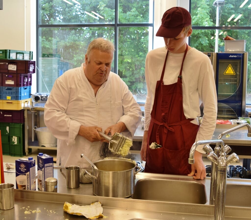 Willem Oosterhof samen met een leerling in de keuken.