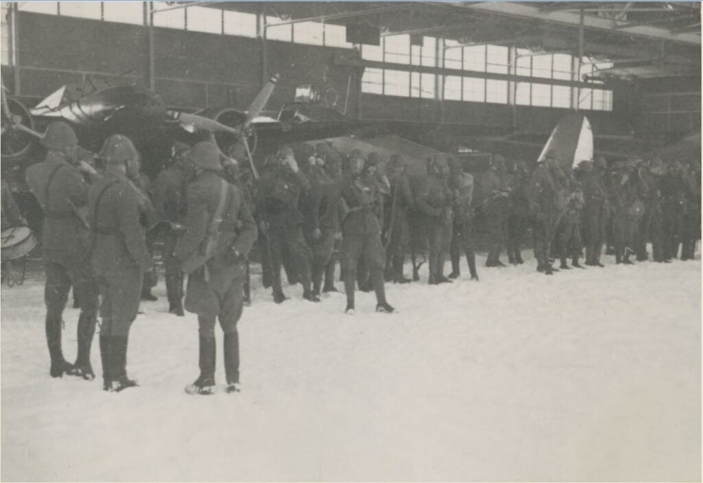 Nederlandse manschappen met gasmasker voor de hangar van vliegveld de Vlijt. 
