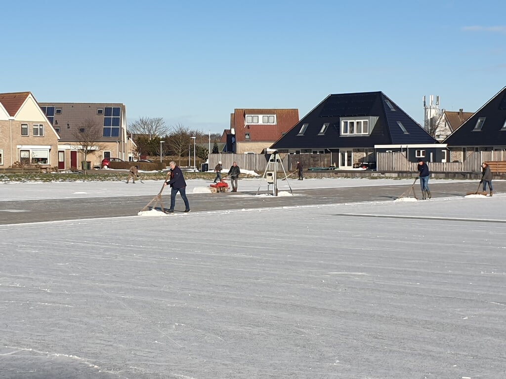 Vrijwilligers in Oudeschild maken de ijsbaan sneeuwvrij.