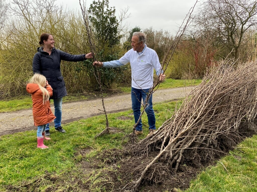 Leo Timmers overhandigt een perenboom aan Daniek van Liere en haar moeder Melanie. 