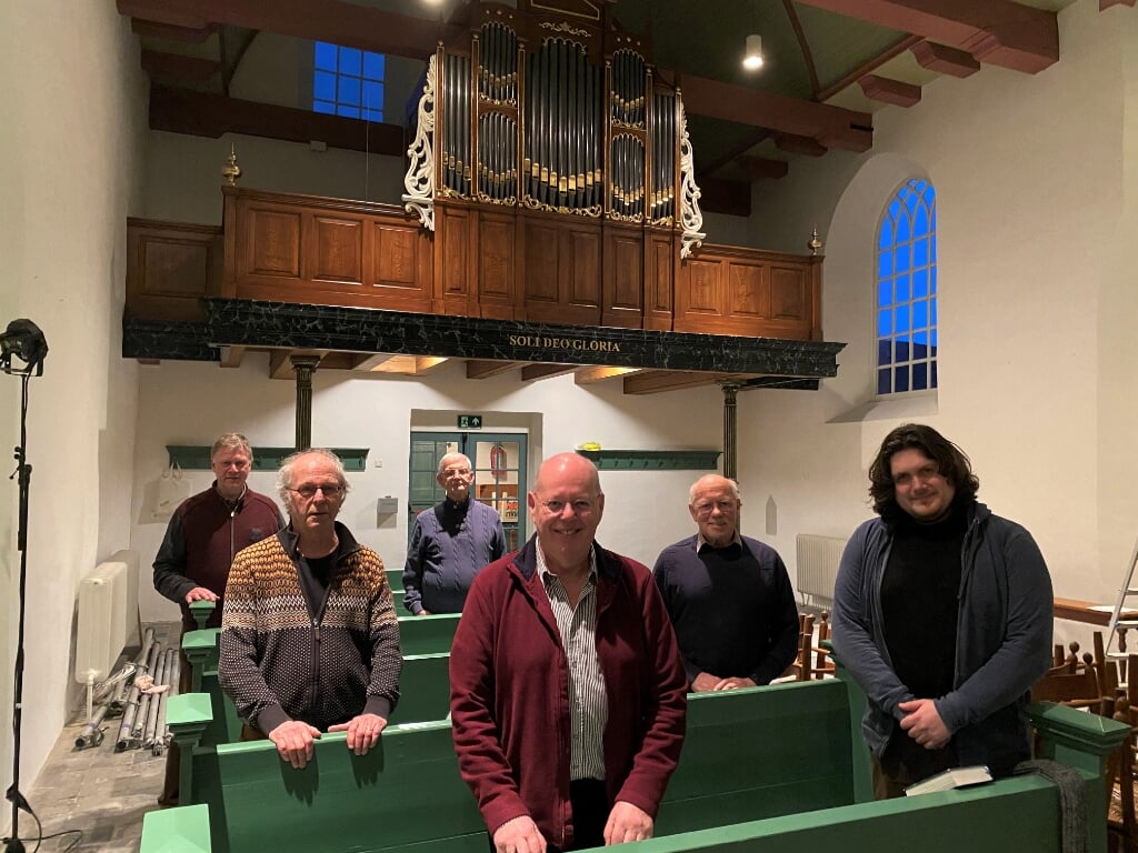 Orgelrestaurateur Sander Booij (rechts), orgelspecialist en -adviseur Stef Tuinstra (midden) en leden van de orgelcommissie bij het kerkorgel. 