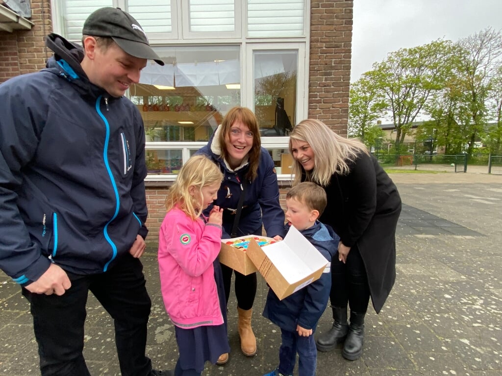 Daniël Eveleens, met zus Sarah en zijn ouders, krijgt een taart van schoolleider Floor Daemen (rechts). 