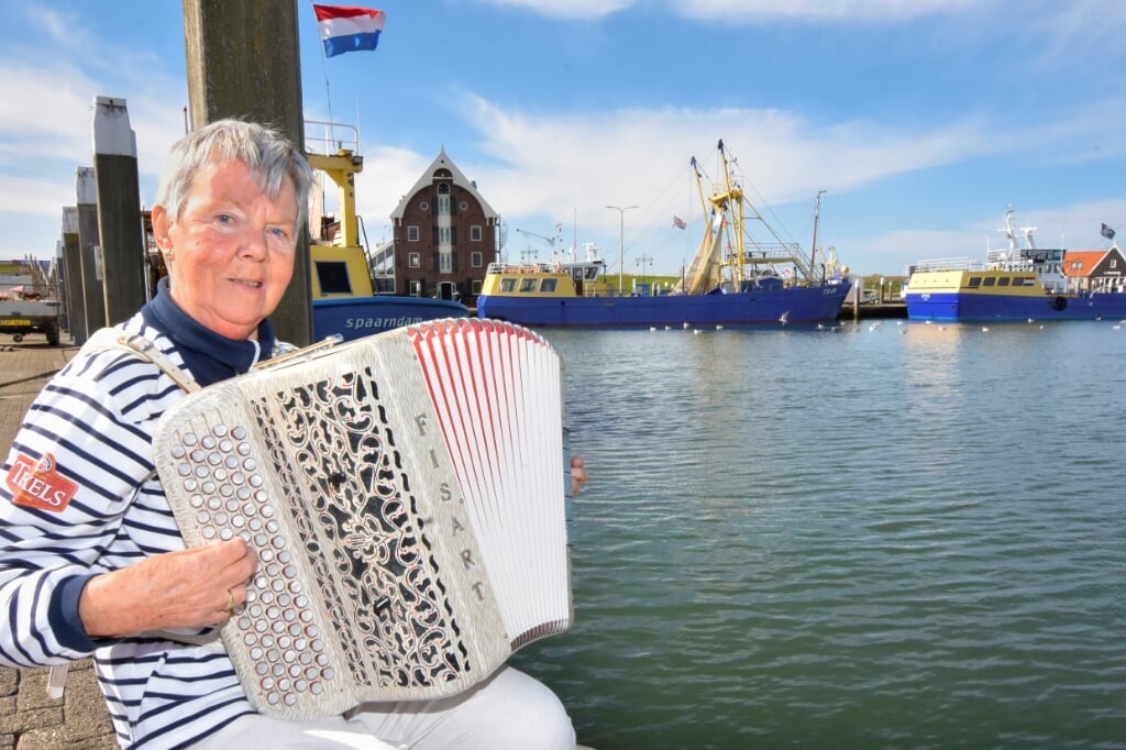 Corrie Witte-Maas met haar accordeon, geportretteerd door René Pop toen ze in 2018 een lintje kreeg. Foto links: met het Visserskoor. 