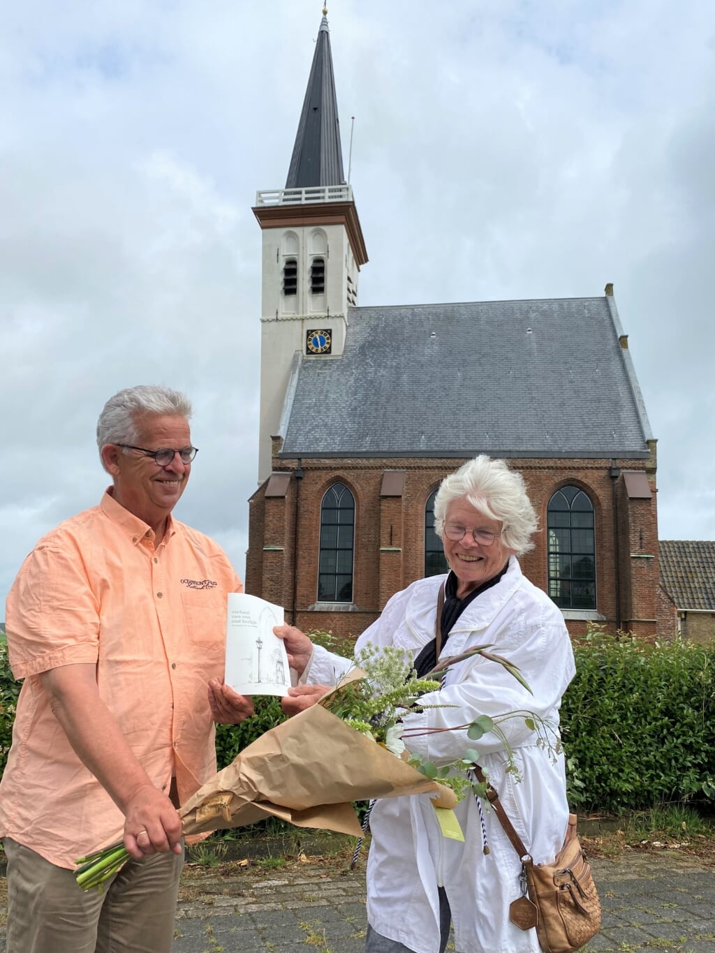 Koster Chris Peters overhandigt Nel Koorn-Kikkert het eerste exemplaar van het opnieuw uitgegeven boekje "Verhaal van een oud kerkje".