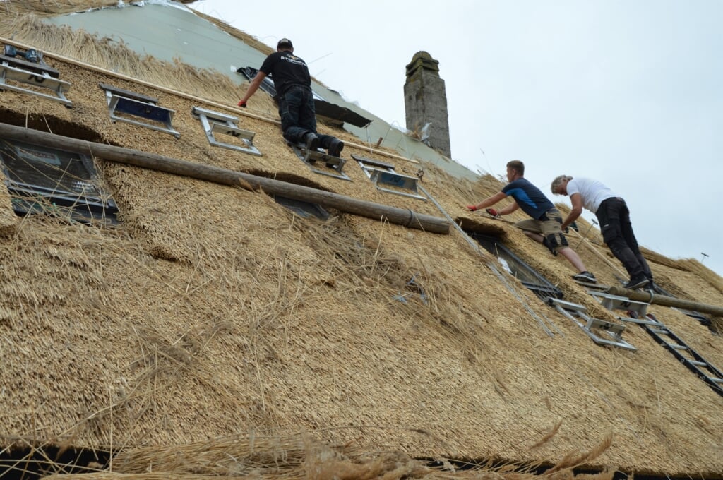 Rietdekker Axel Wetsteen met zijn medewerkers vernieuwen een dak van een stolp. 