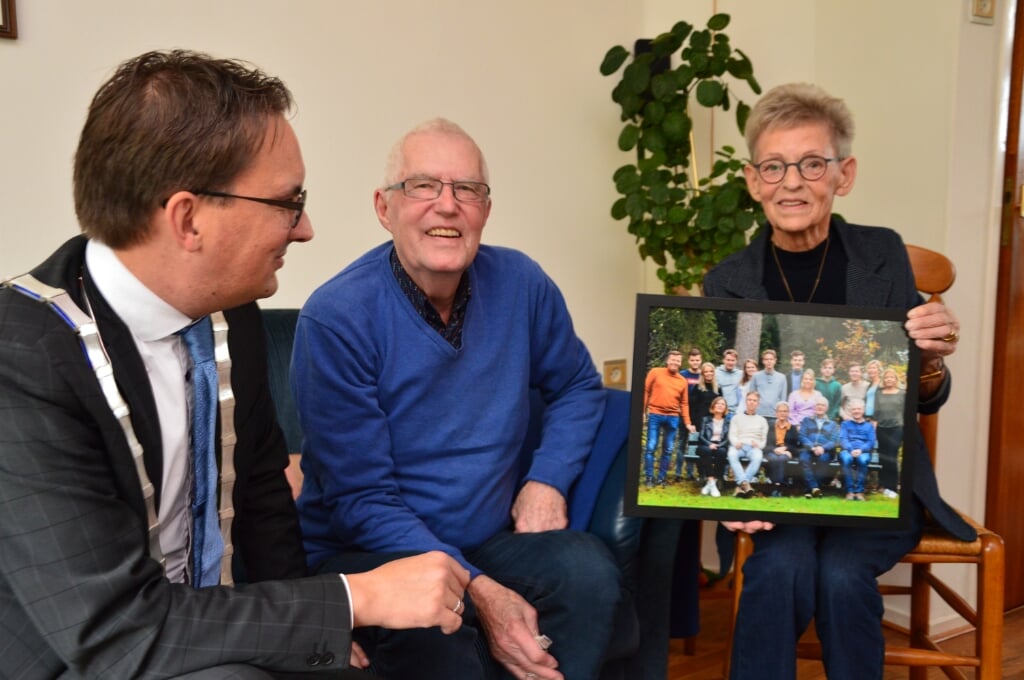 Bram en Dide van Dijk tonen bij hun 60-jarig huwelijk de foto met hun kinderen en kleinkinderen aan burgemeester Michiel Uytdehaag. 