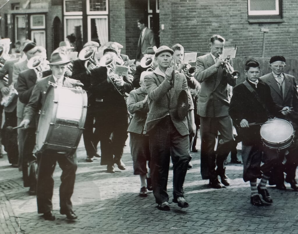 September 1956. DEK marcheert. Herkenbaar zijn Gerrit Kiljan (grote trom), Gerrit Coevert (bekken), Dick Smit (bugel), Willem Bakker (trompet), Martien Witte (kleine trom) en dirigent Bousma.