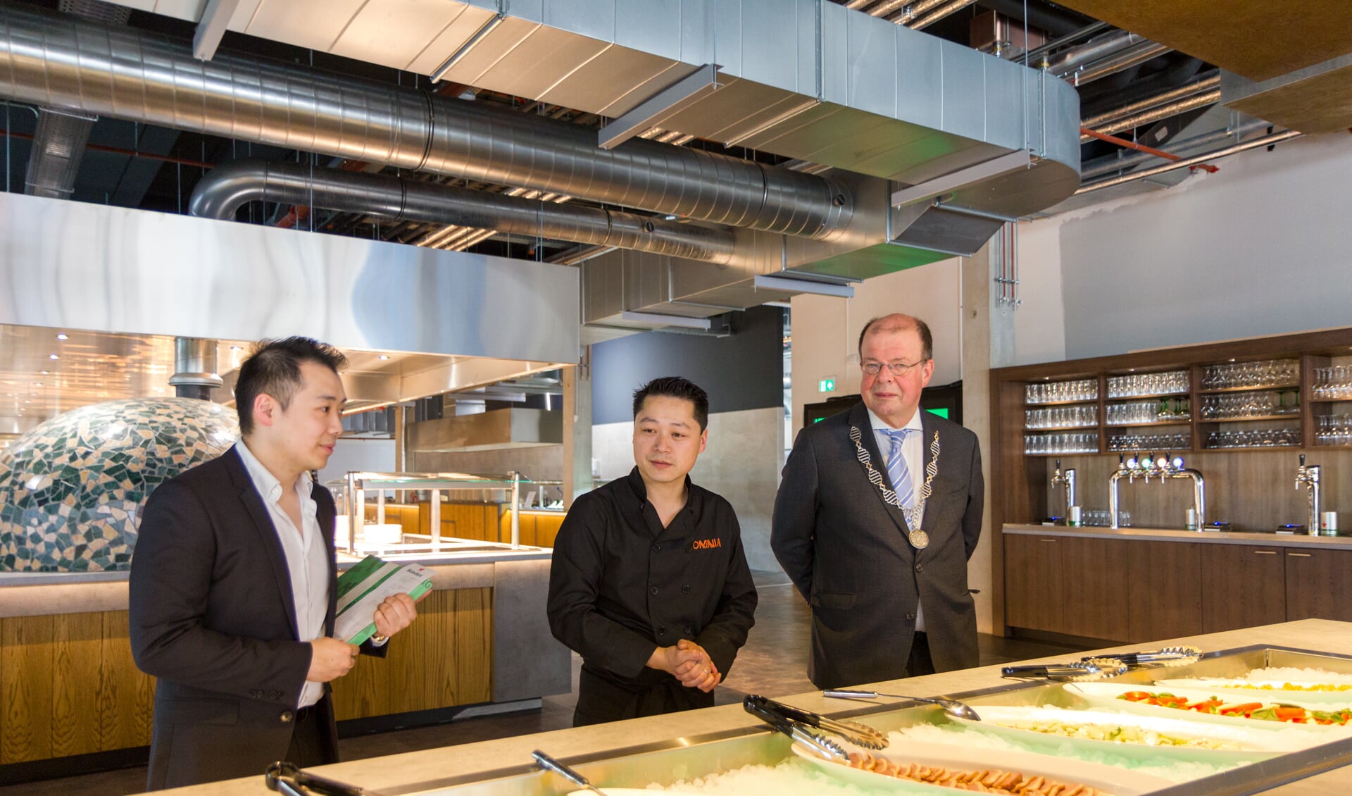 André Chen en Haiyi Shan laten burgemeester Tom van Mourik het uitgebreide visbuffet zien. 