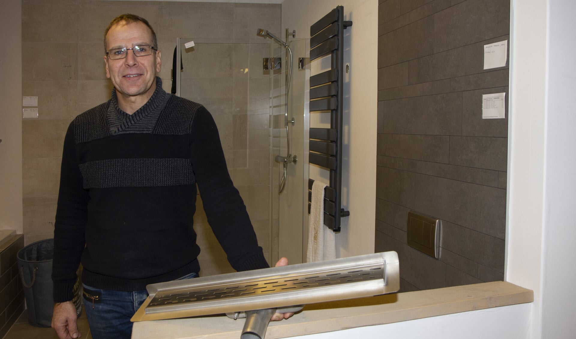 Verkoopadviseur Klaas Algra toont de drain die onder de vloer komt in een moderne badkamer. Gegarandeerd lekvrij.