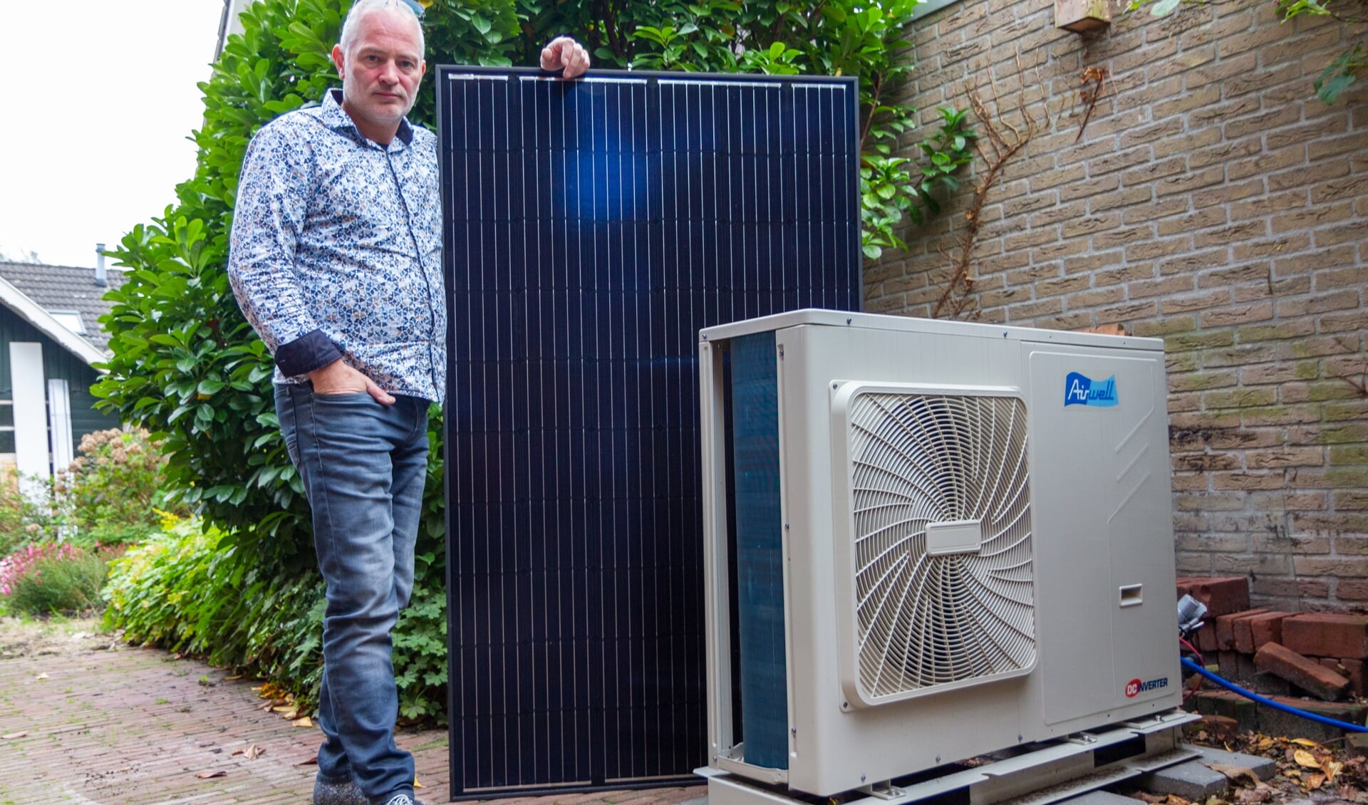 Jurgen Dijkstra bij de warmtepomp. Het losse zonnepaneel  gebruikt hij voor uitleg aan klanten.