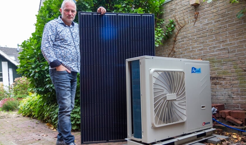 Jurgen Dijkstra bij de warmtepomp. Het losse zonnepaneel gebruikt hij voor uitleg aan klanten.