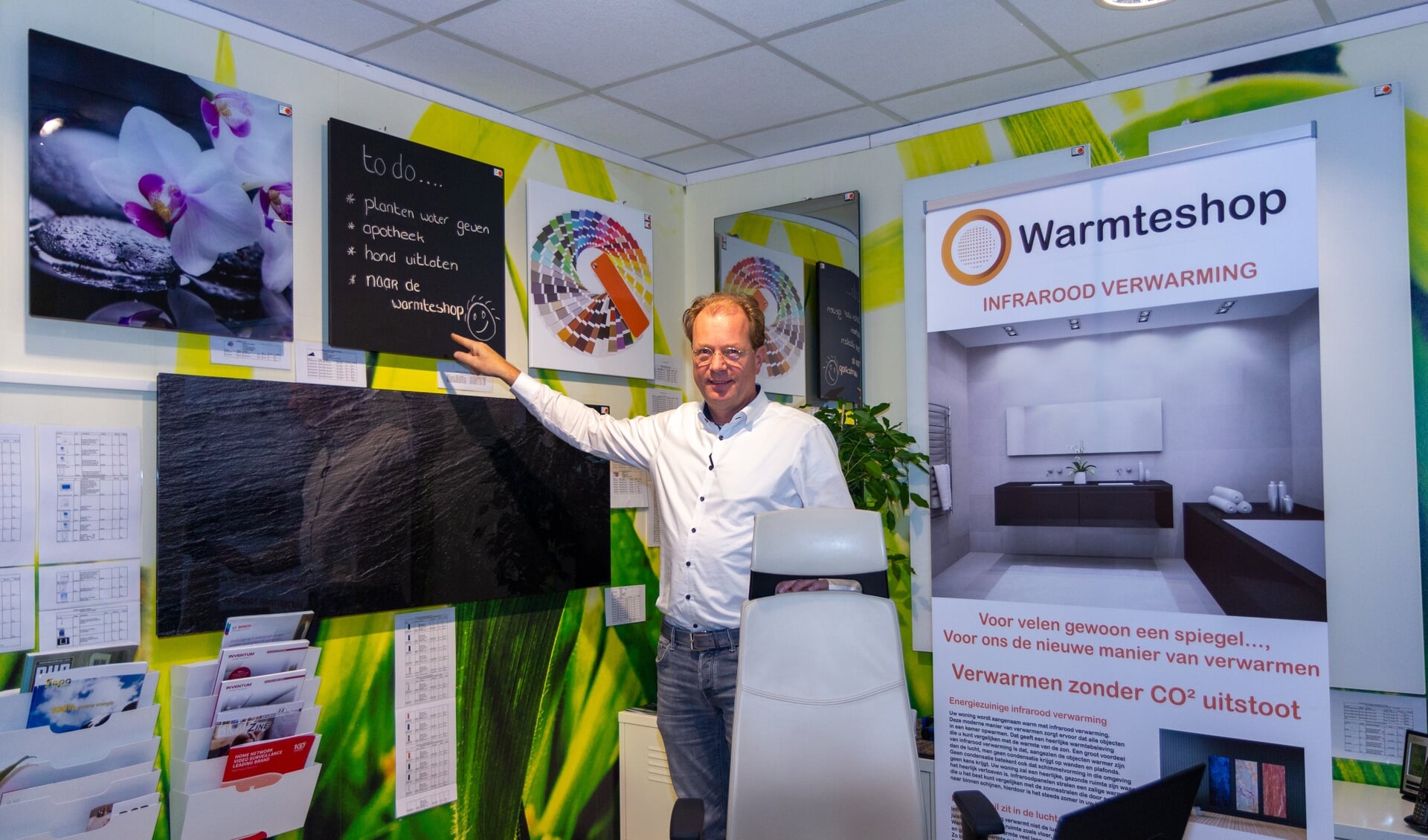 Erik Meijer in De Warmteshop bij een aantal infraroodpanelen, waarvan één zelfs voorzien is van een krijtbord.