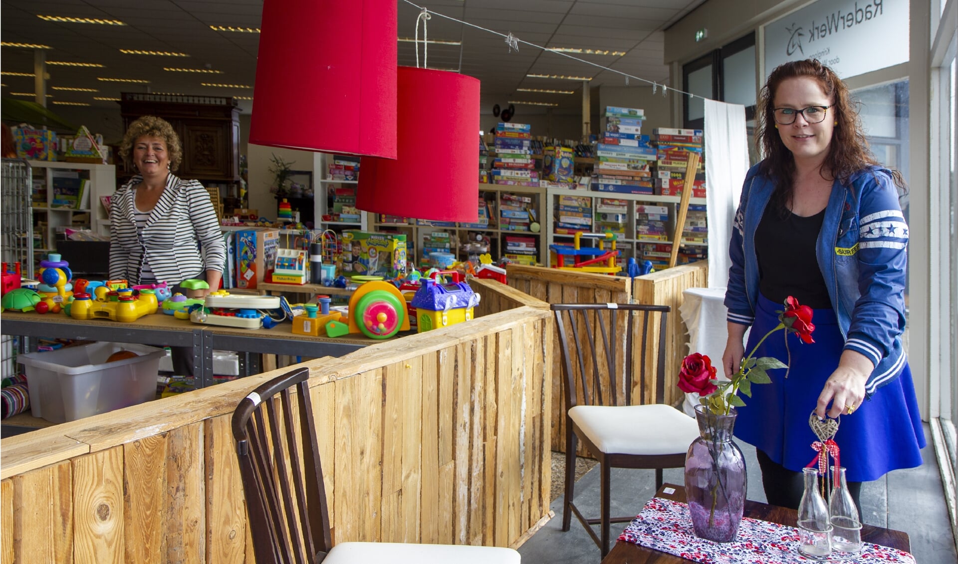 Boukje Hollema is medewerker op de speelgoedafdeling van kringloopwinkel Raderwerk in Buitenpost. Ze past de cursus 'Etaleren kun je leren' direct toe in de praktijk. Op de achtergrond Sylvia Dillema.