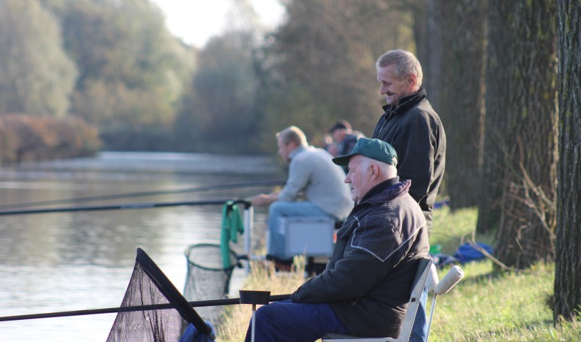 De hengelaars van 't Snoerke hebben zo nu en dan tijd voor een praatje, maar ze hebben vooral oog voor hun dobber en de vis die ze willen vangen.