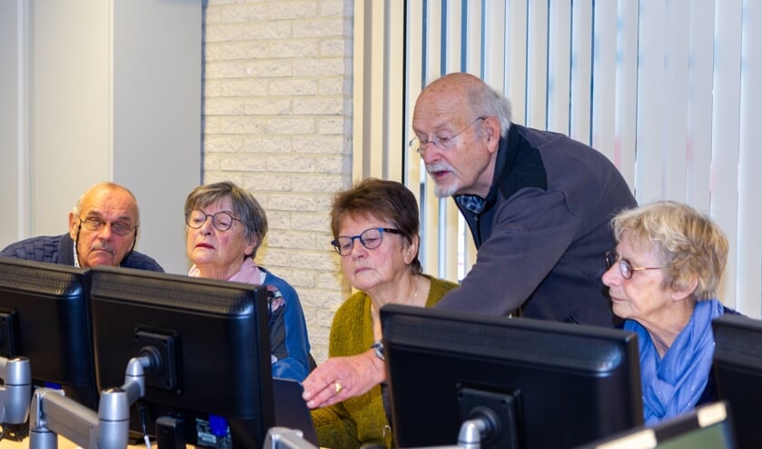 De vrijwilligers Fred Drost (uiterst links) en Pabe Wiersma tijdens een les over Windows 10.
