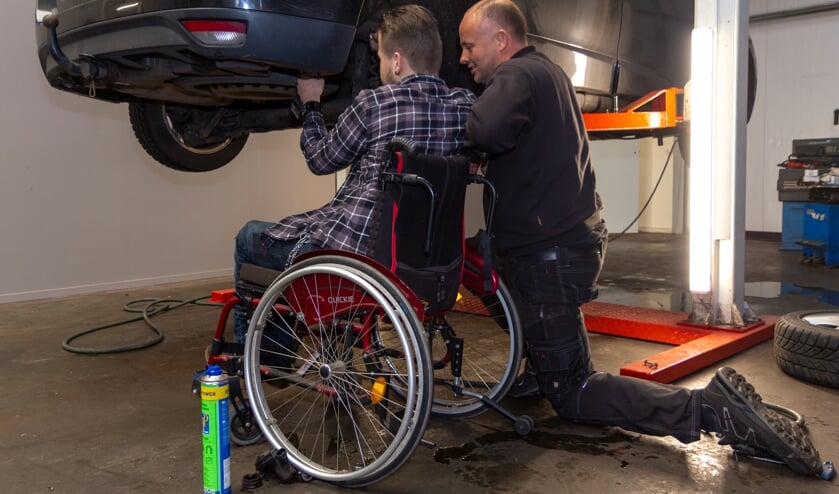 Hylke Walstra sleutelt samen met Kylian aan een auto.
