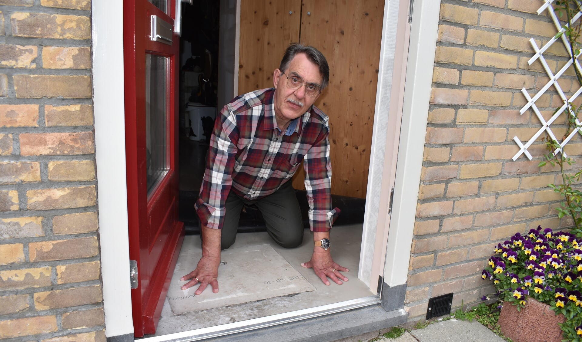Wim de Graaf toont de vochtplek onder het vloerkleed achter de voordeur. 