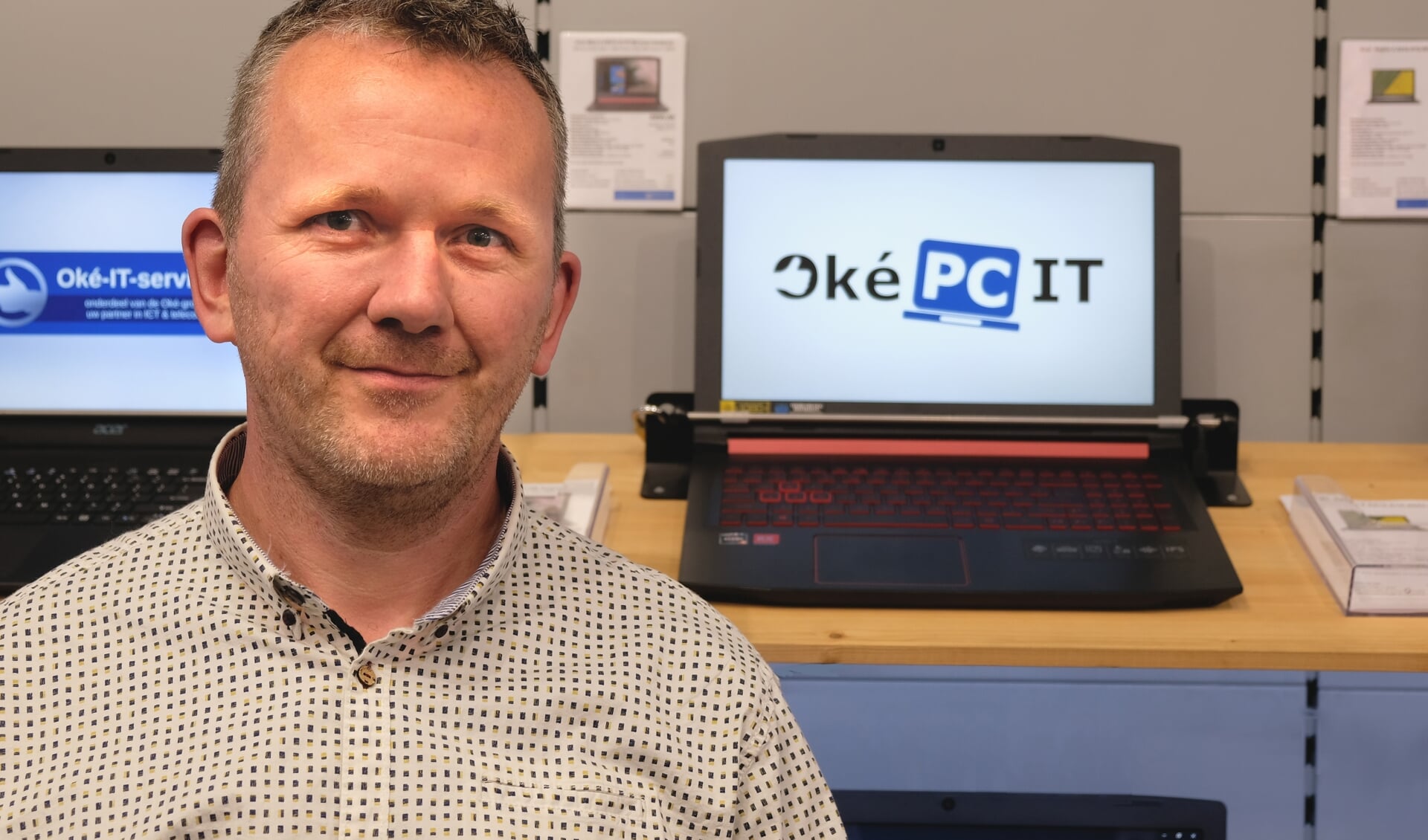 Ronald Zijlstra, met op de laptop achter hem het nieuwe logo van Oké-PC.