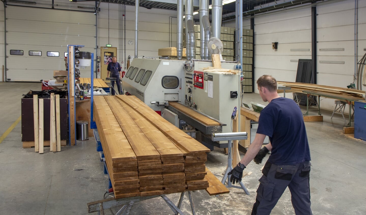 Jan Kroes en Arend Castelein schaven het hout in de werkplaats voor machinale houtbewerking tot planken met veer en groef.