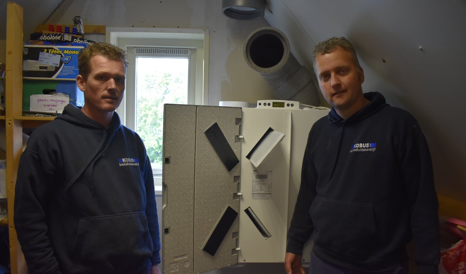 Installateurs Jappie de Vries (links) en Bauke Ykema bij de nieuwe warmterugwinventilator in huize Albada in Garyp. Deze woning was één van de eerste in Garyp die 'aardgasvrij' is gemaakt.