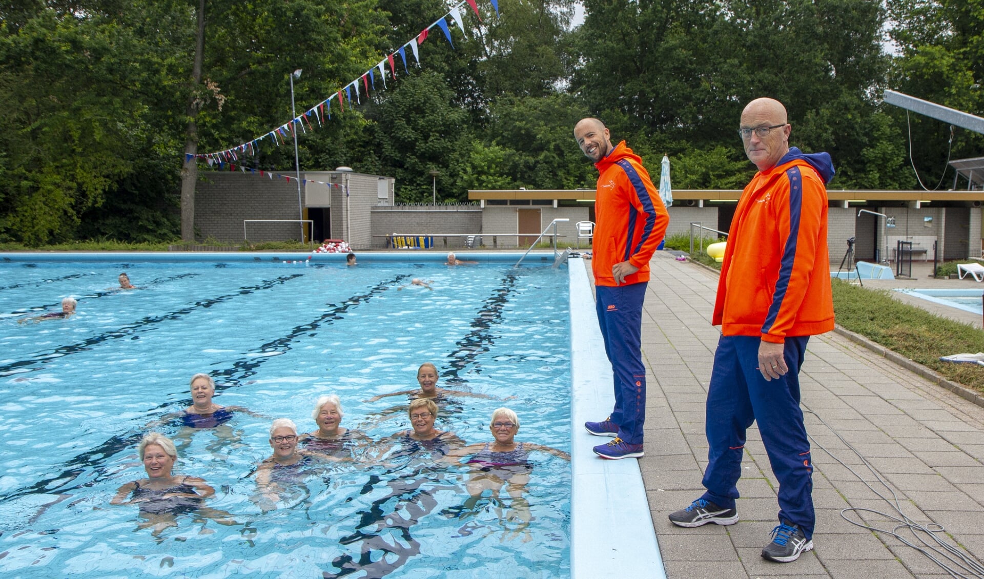Het zwembad De Sawn Doarpen in Gytsjerk in juli 2019, met de badmeesters Ben Douwes (links) en Anton Nijboer. In het water enkele ouderen, die vitaal blijven dankzij regelmatig zwemmen.