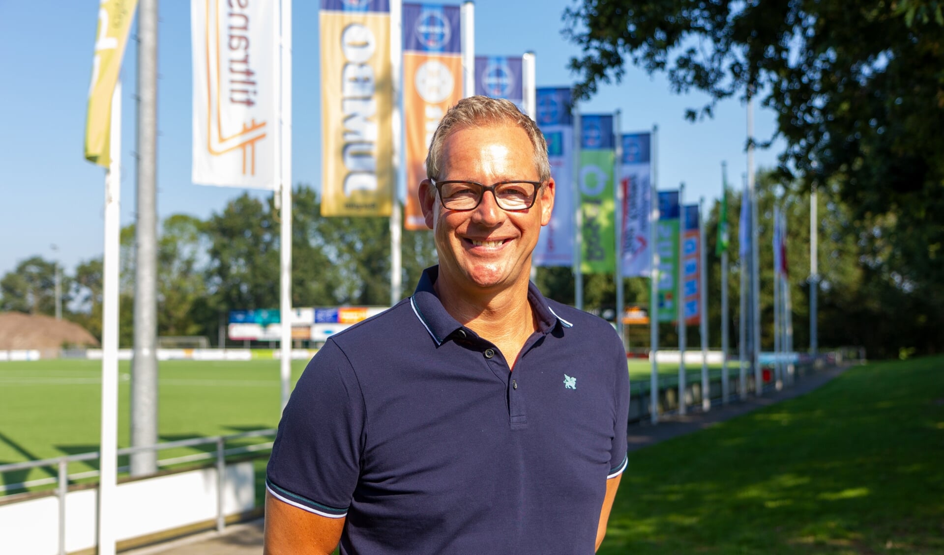 Voorzitter Dirk van der Woude van FC Burgum voor de sponsorvlaggen met het nieuwe FC Burgum logo. 