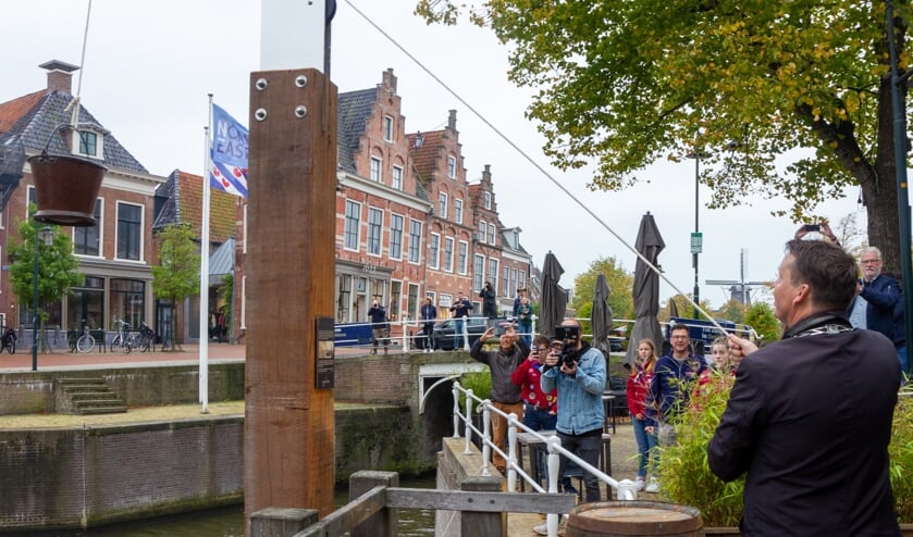 Burgemeester Johannes Kramer takelt de emmer met water het laatste stuk naar boven.