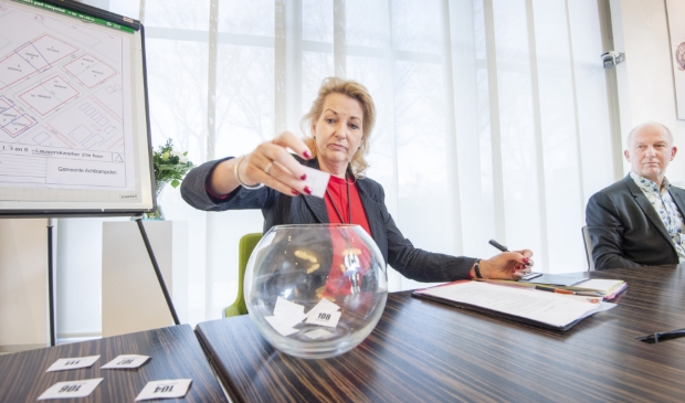 De notaris trekt de lootjes, wethouder Harjan Bruining kijkt toe.