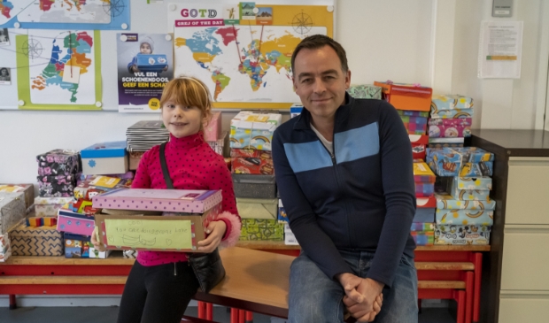 <p>Groep 5-leerling Rianne Brandsma met haar doos die zo vol is dat hij bijna niet dicht wil en locatieleider Jaap Wieb Eelkema. </p>