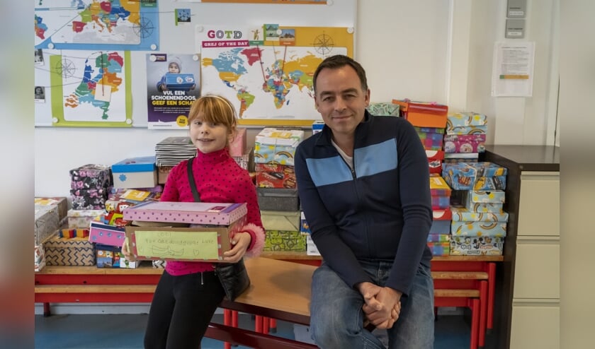<p>Groep 5-leerling Rianne Brandsma met haar doos die zo vol is dat hij bijna niet dicht wil en locatieleider Jaap Wieb Eelkema. </p>