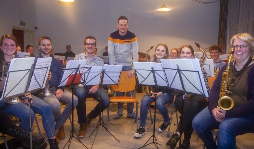 Dirigent Ido Kempenaar te midden van de orkestleden met wie hij zondag in Buitenpost een bijzonder evenement presenteert.