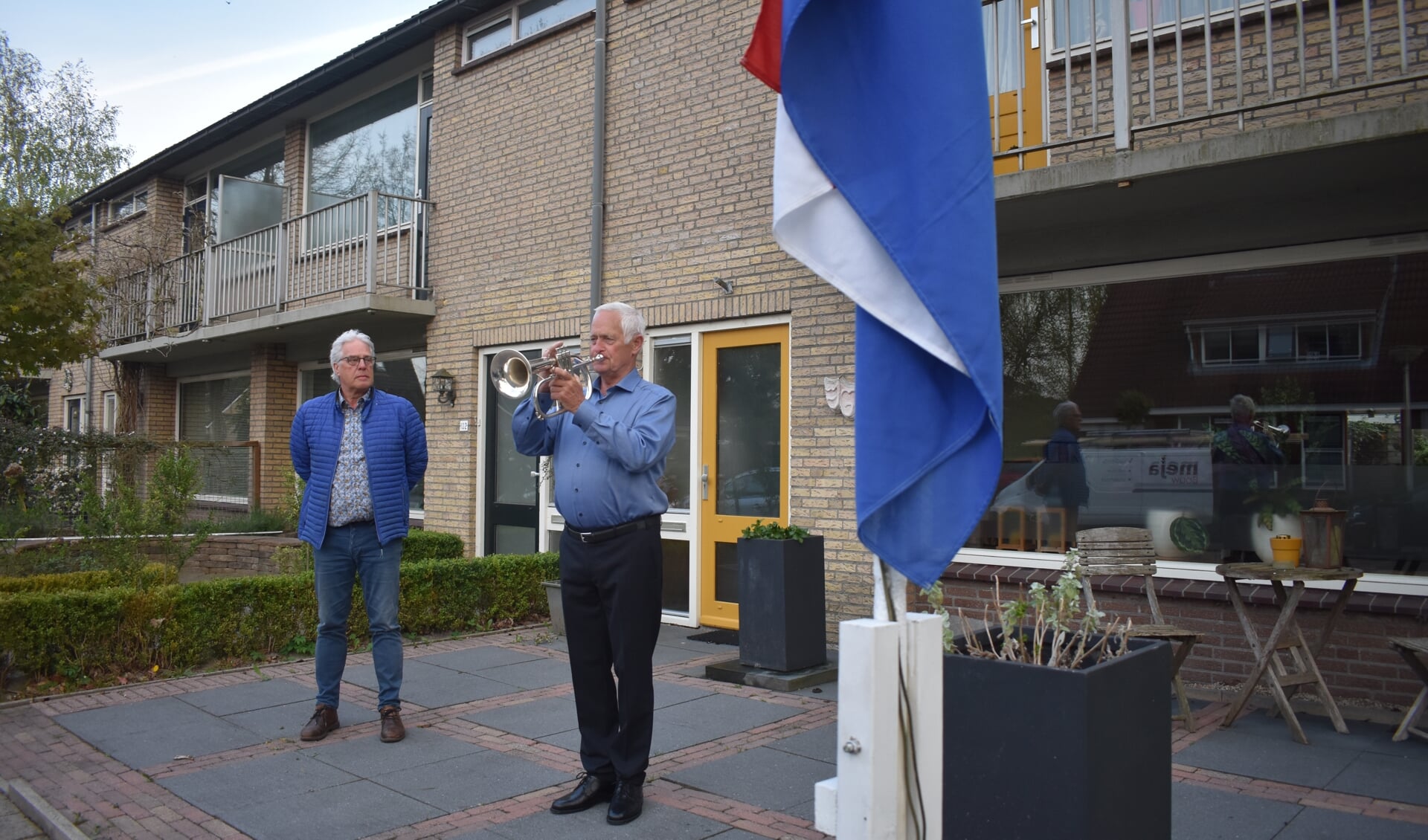 De Burgumers Dick Jansen (links) en Piet Kleefstra (op bugel) oefenen de herdenking voor maandag 4 mei, 's avonds twee minuten voor acht. De vlag mag maandag overdag al halfstok hangen.
