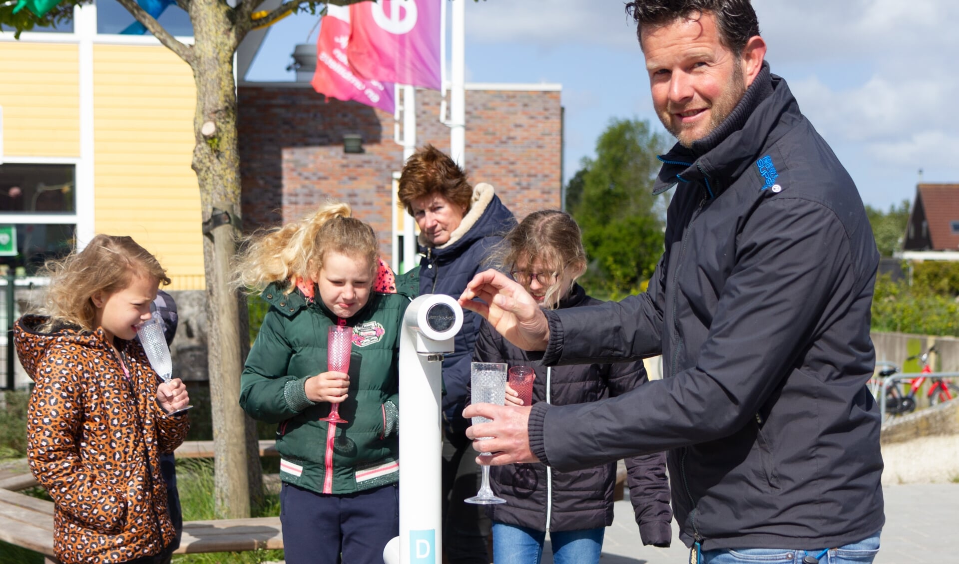 Schooldirecteur Nico Woudwijk tapt een glaasje vers water bij het nieuwe watertappunt. 