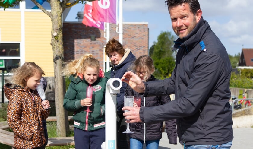Schooldirecteur Nico Woudwijk tapt een glaasje vers water bij het nieuwe watertappunt.