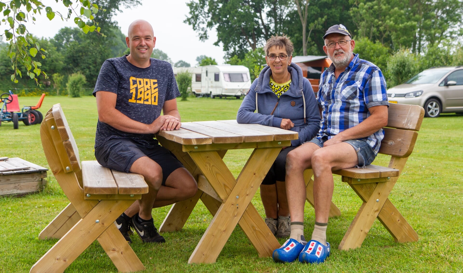 Jan Willem, Baukje en Gjalt Bouma aan een picknicktafel midden op de minicamping. Scan de foto met de ActiefPlus-app voor een filmpje.