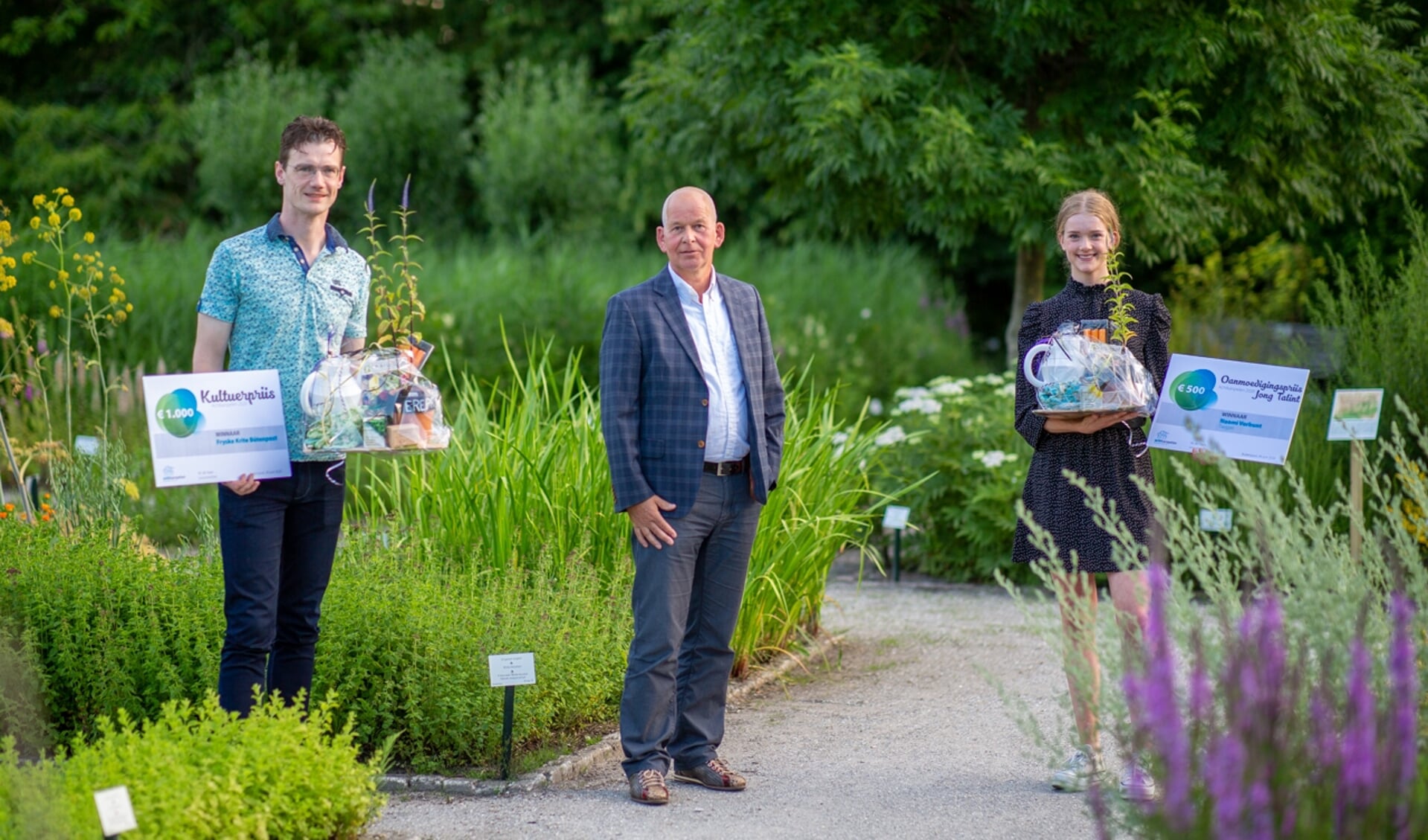 De winnaars met de cheques: 1.000 euro voor Arnold Jan Ruisch van Fryske Krite Bûtenpost, 500 euro voor Naomi Verbunt. In het midden wethouder Max de Haan.