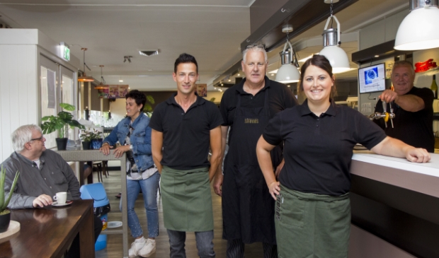De keuken- en bedieningsmedewerkers van Sirenes in Drachten, van links naar rechts Gerrie de Boer, Louwe Nieuwenhuis en Iris Roufs. Op de achtergrond de ondernemers Gretha de Vries in gesprek met Nanne van der Veen van Apuls (zittend op de stoel) en Jan de Vries (achter de tap).