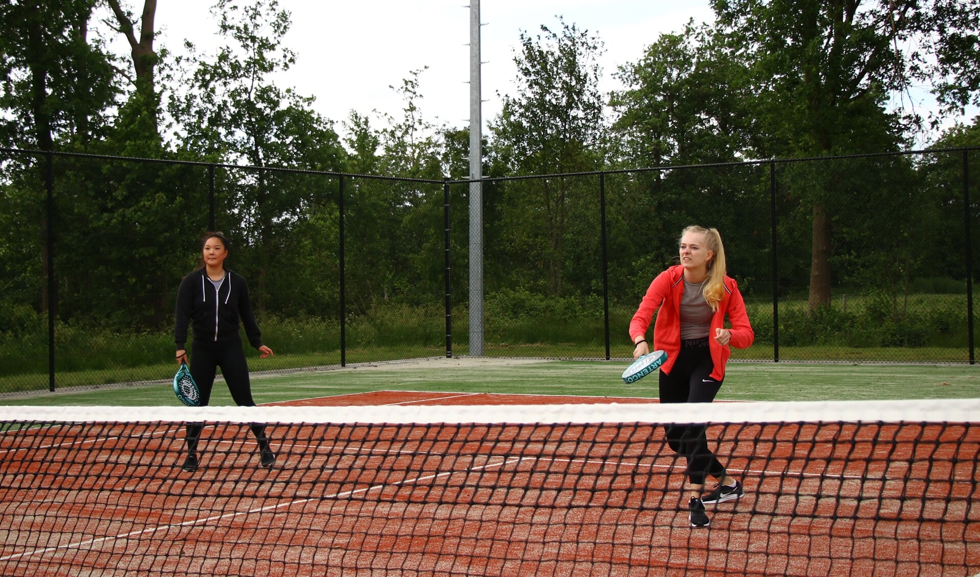 Anne Yoo Jacobi en Ilse Jansma op de tennisbanen van De Kreilen. Ze tennissen met een padelracket. Scan ook de foto voor het filmpje met bestuurslid Wiebren Riemersma.