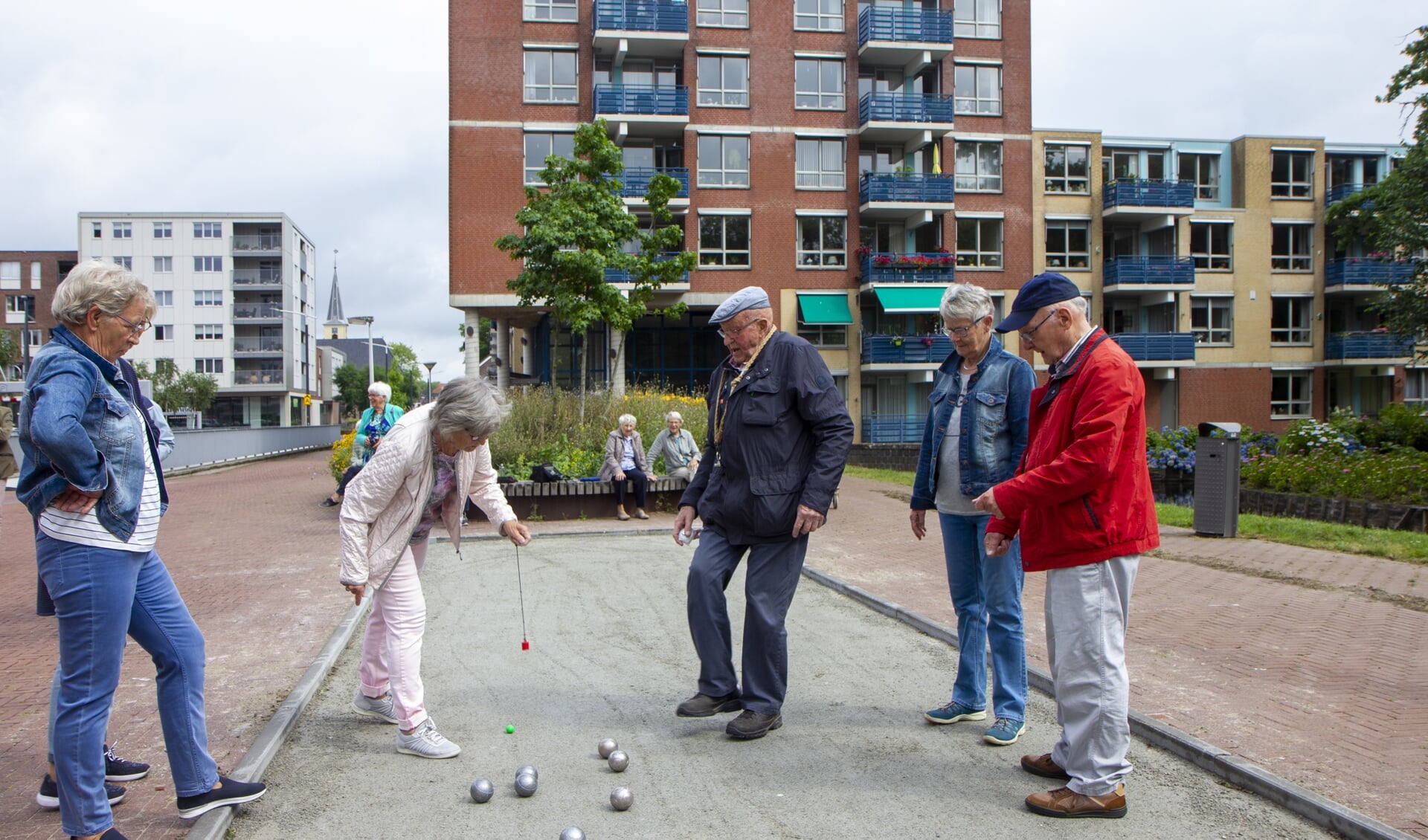 Hennie Poortvliet pakt een jeu de boulesbal op met een magneet onder toeziend oog van Site Visser (midden) en andere flatbewoners.
